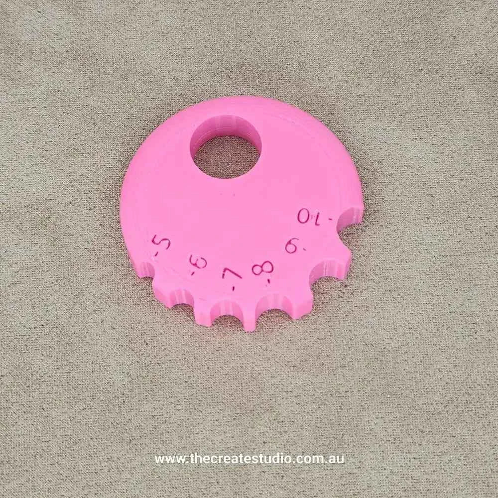 Pink round rib tool for ceramics with various size measurement markings for precise pottery shaping