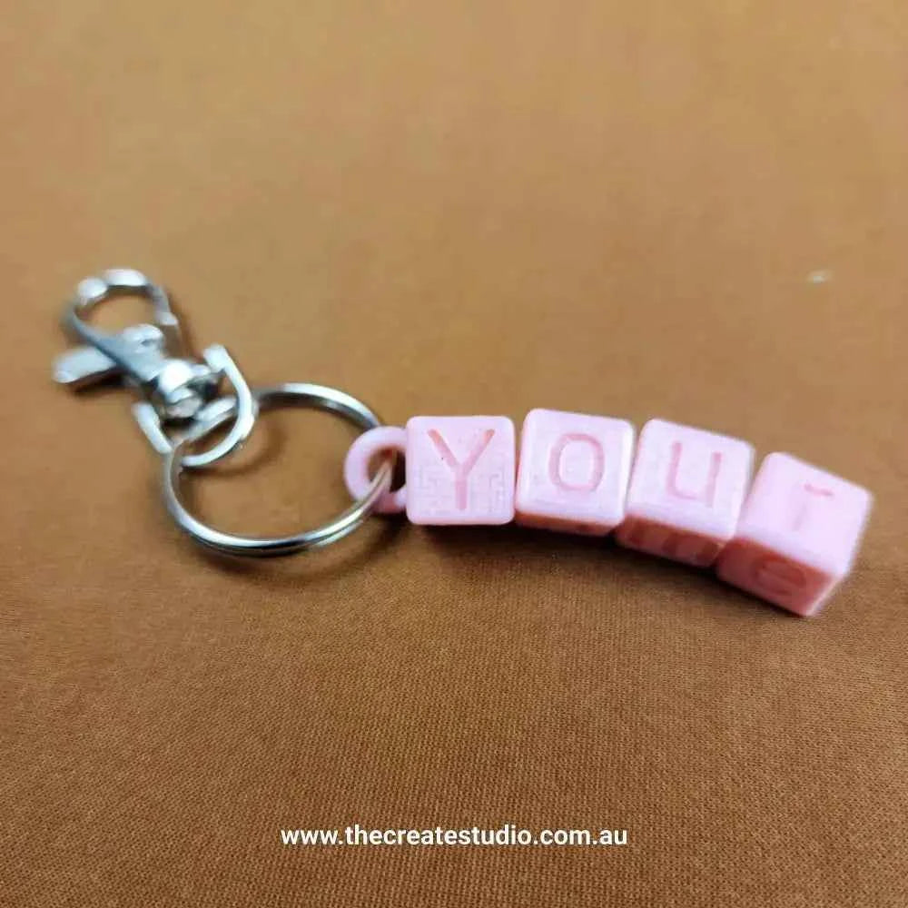 Personalised name keychain in pink with letter blocks spelling 'YOU' for customised gifts