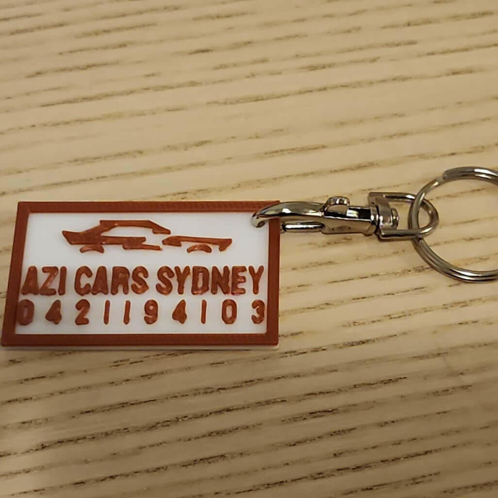 Custom keychains for companies featuring AZI Cars Sydney branding and contact details