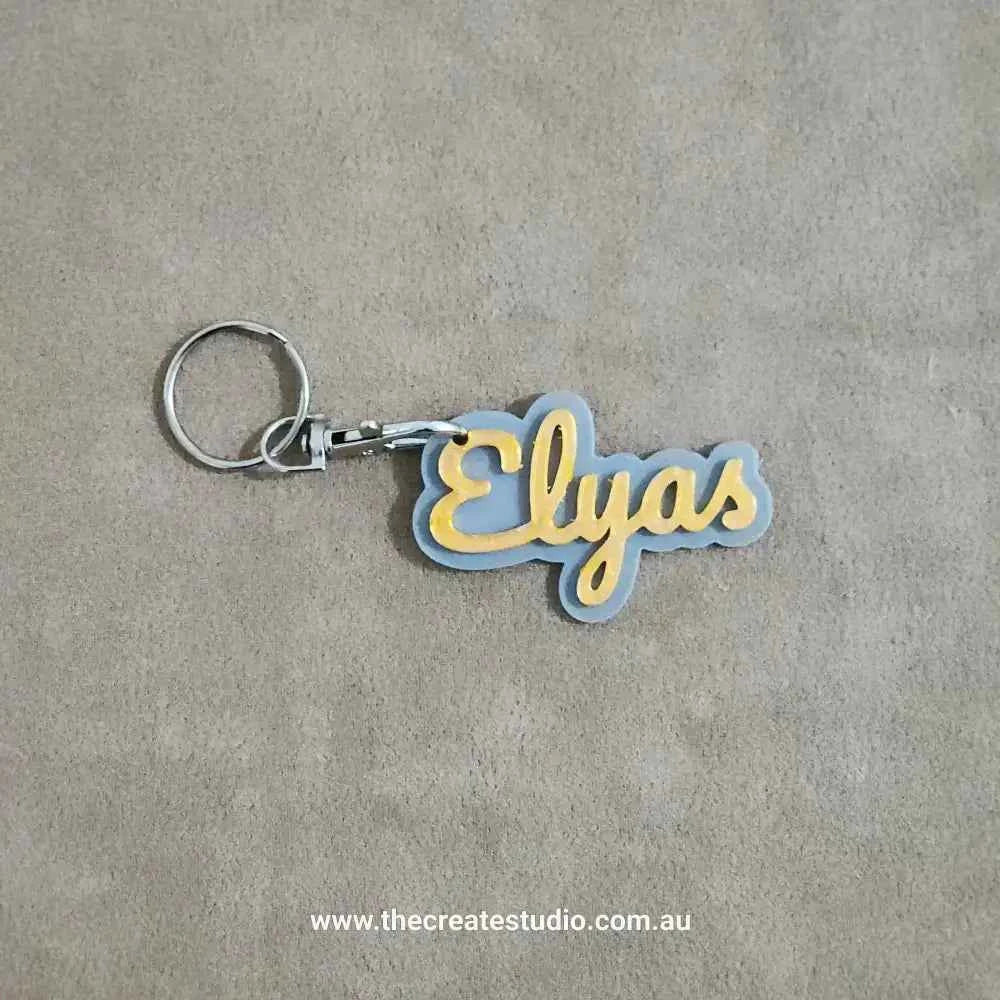 Custom name keychain featuring the name Elyas in a stylish design with grey and yellow colours