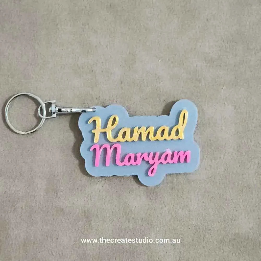 Custom name keychain featuring the names Hamad and Maryam in vibrant colours on a soft background