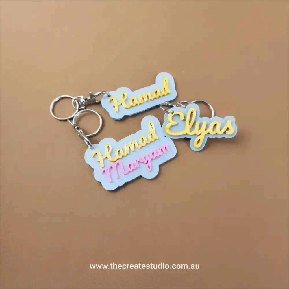 Custom name keychain set featuring name styles Hamad and Elysas with vibrant colours and metal rings
