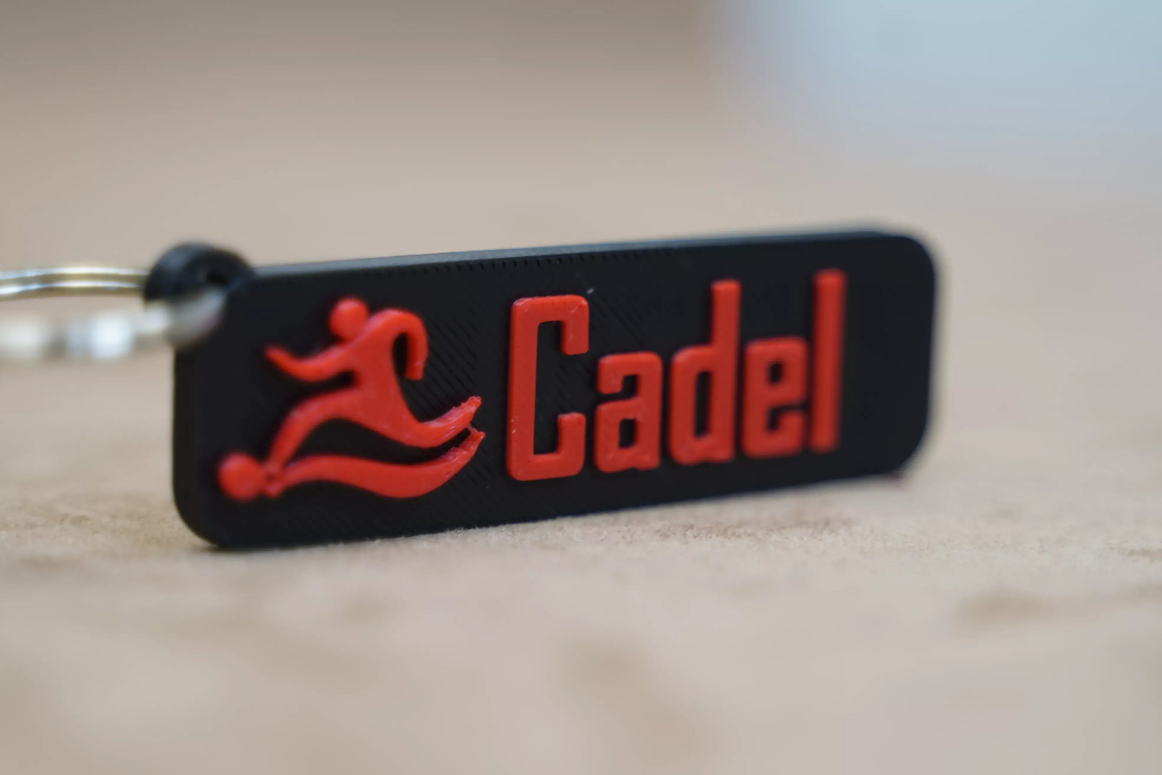 Personalised football keychain featuring the name Cadel in bold red lettering on a black background
