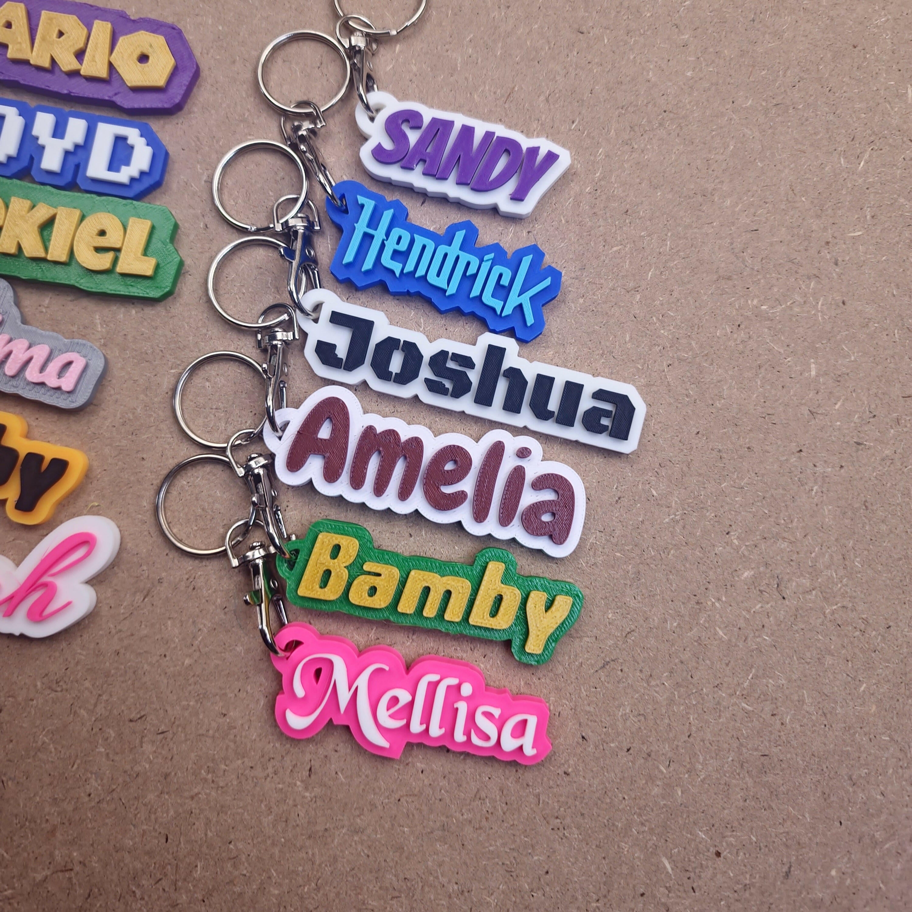 Personalised keychains with modern fonts in various colours featuring names like Sandy and Joshua