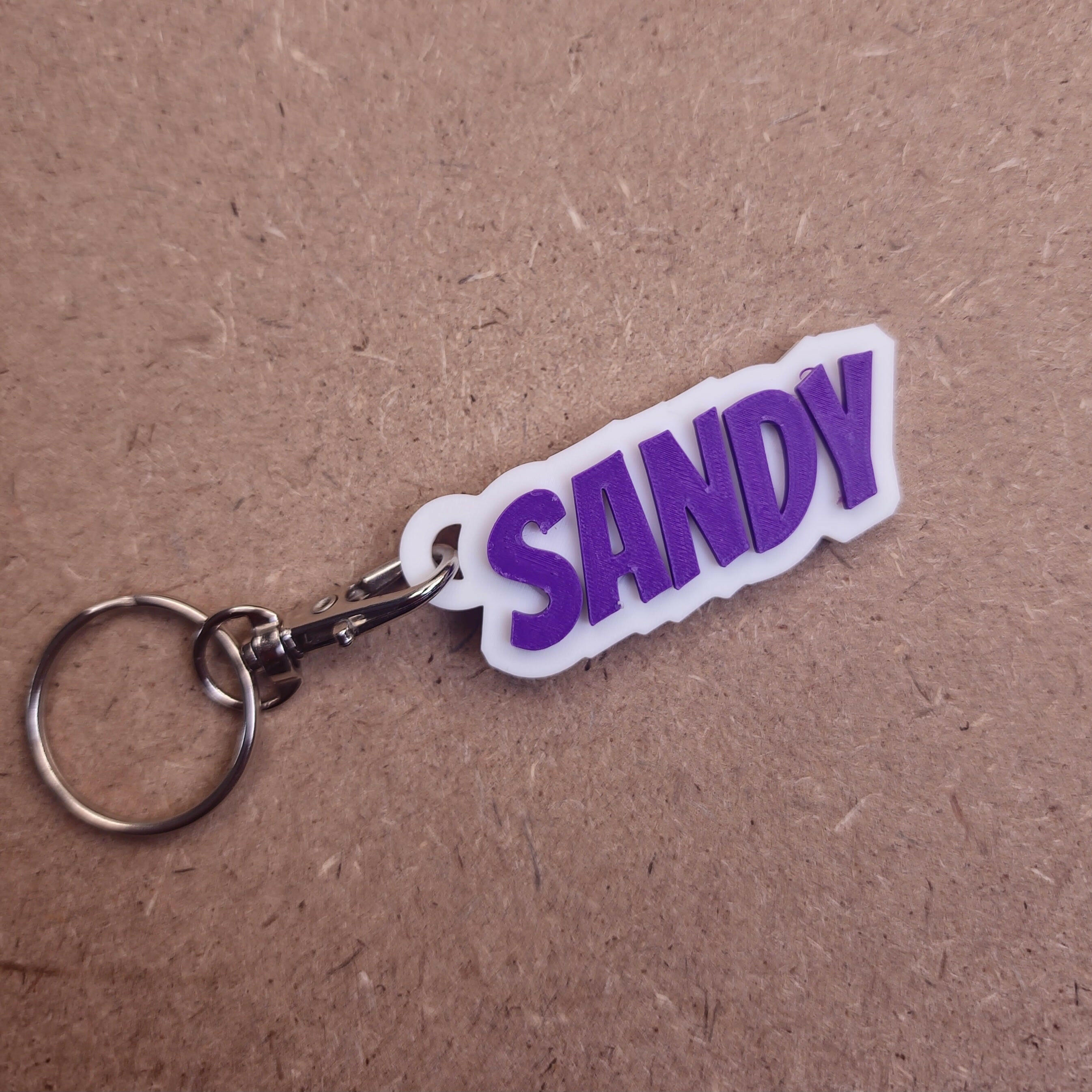 Personalised keychains with modern fonts featuring the name Sandy in purple lettering