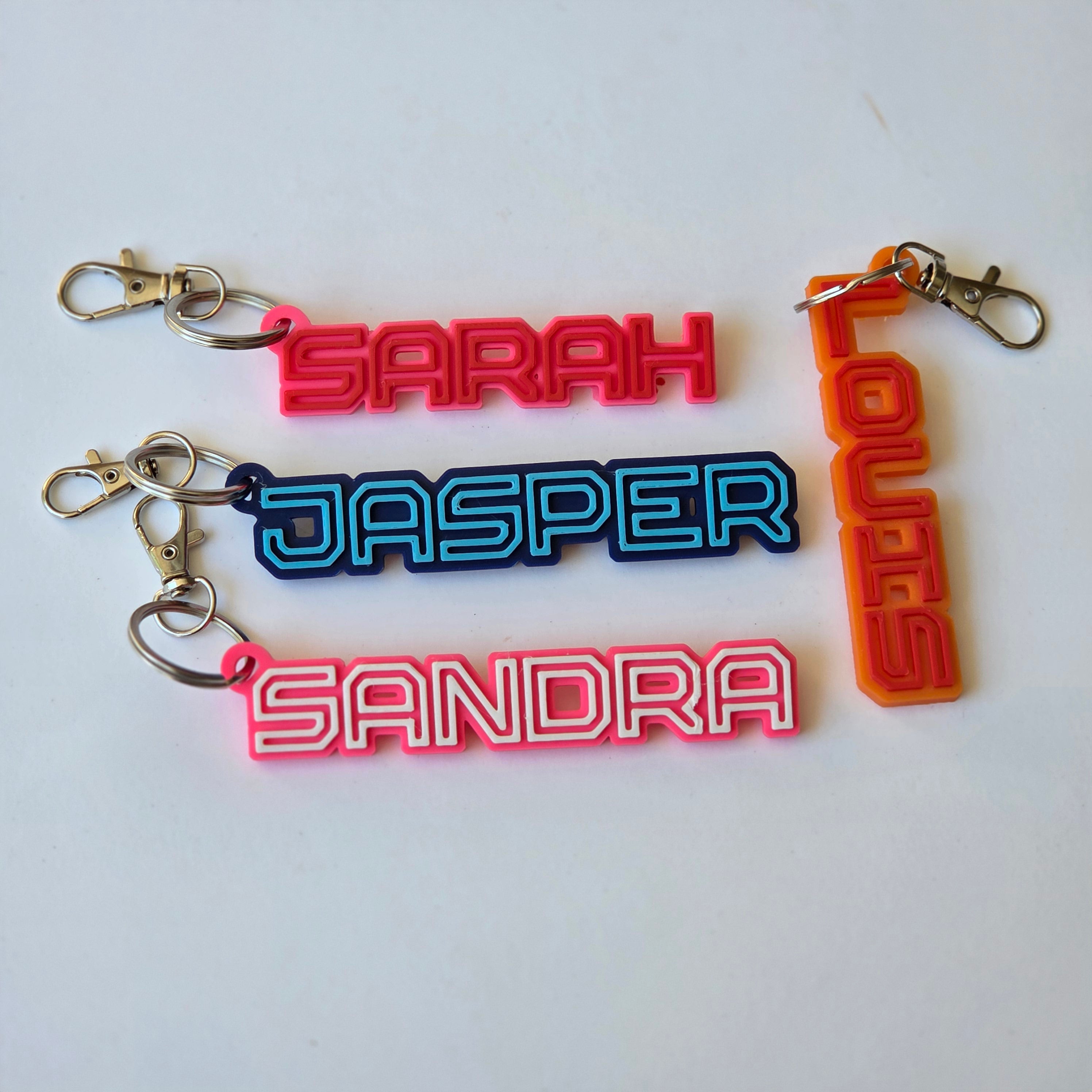 Personalised name keyring in various colours featuring names Sarah, Jasper, and Sandra