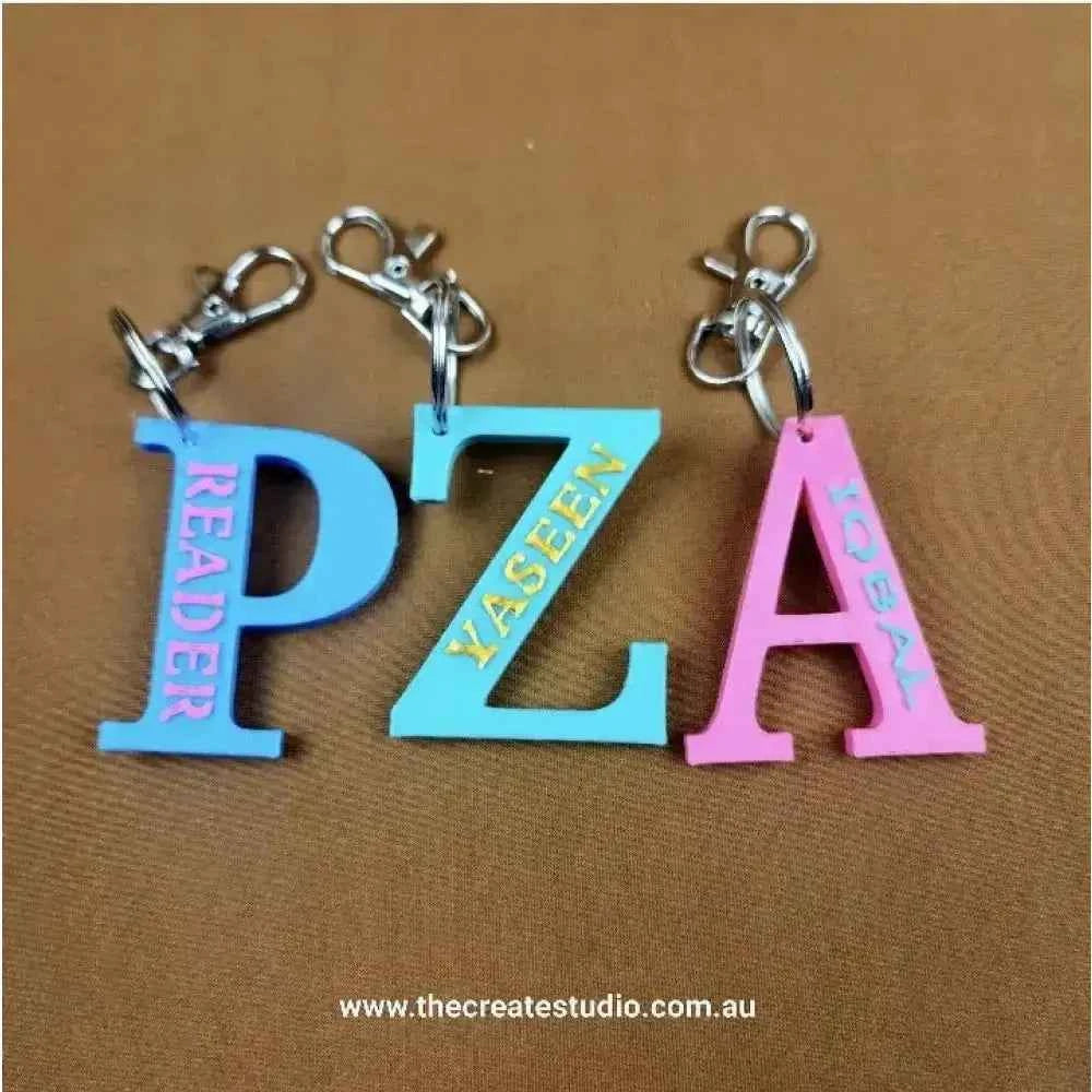 Three colourful personalised initial keychains featuring letters PZA, YASEEN, and READER