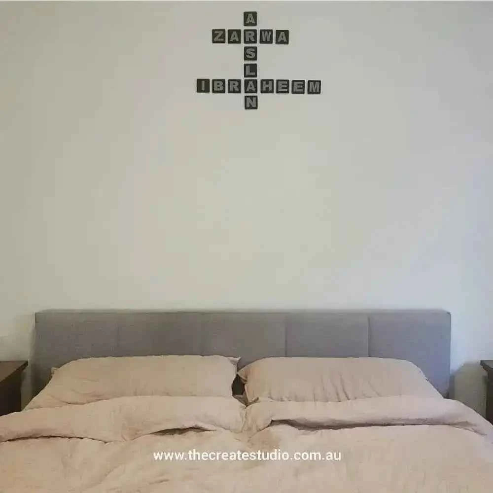 Personalised family tree gift wall art in black lettering above a styled bed with neutral bedding
