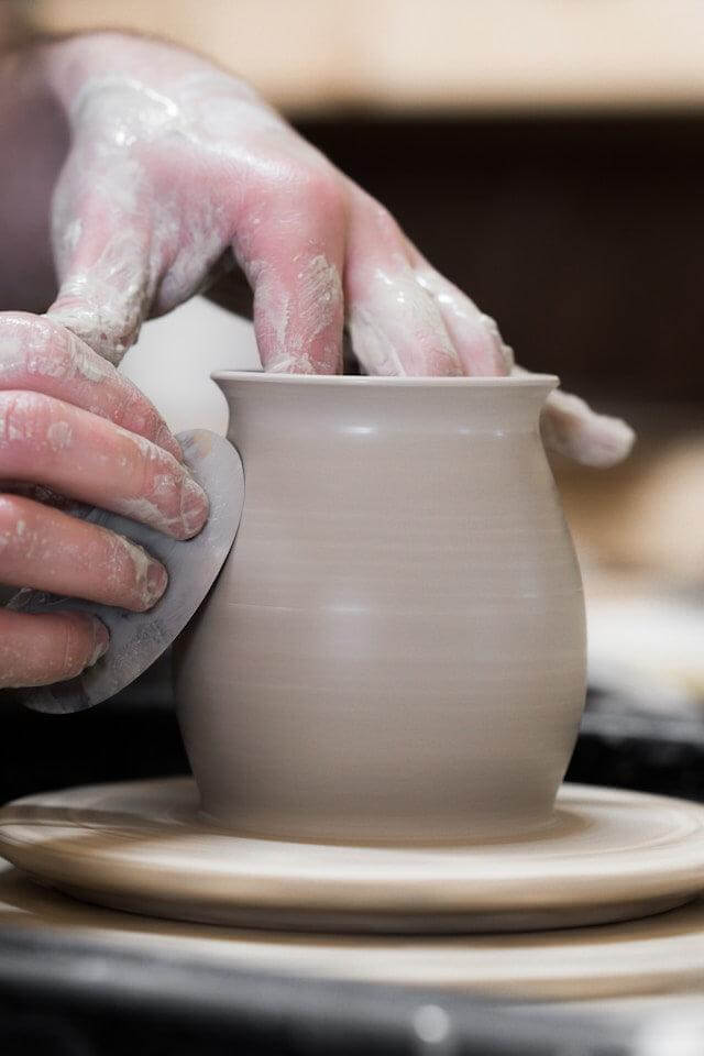Artisan shaping ribbed pottery mugs on the pottery wheel, showcasing expert craftsmanship