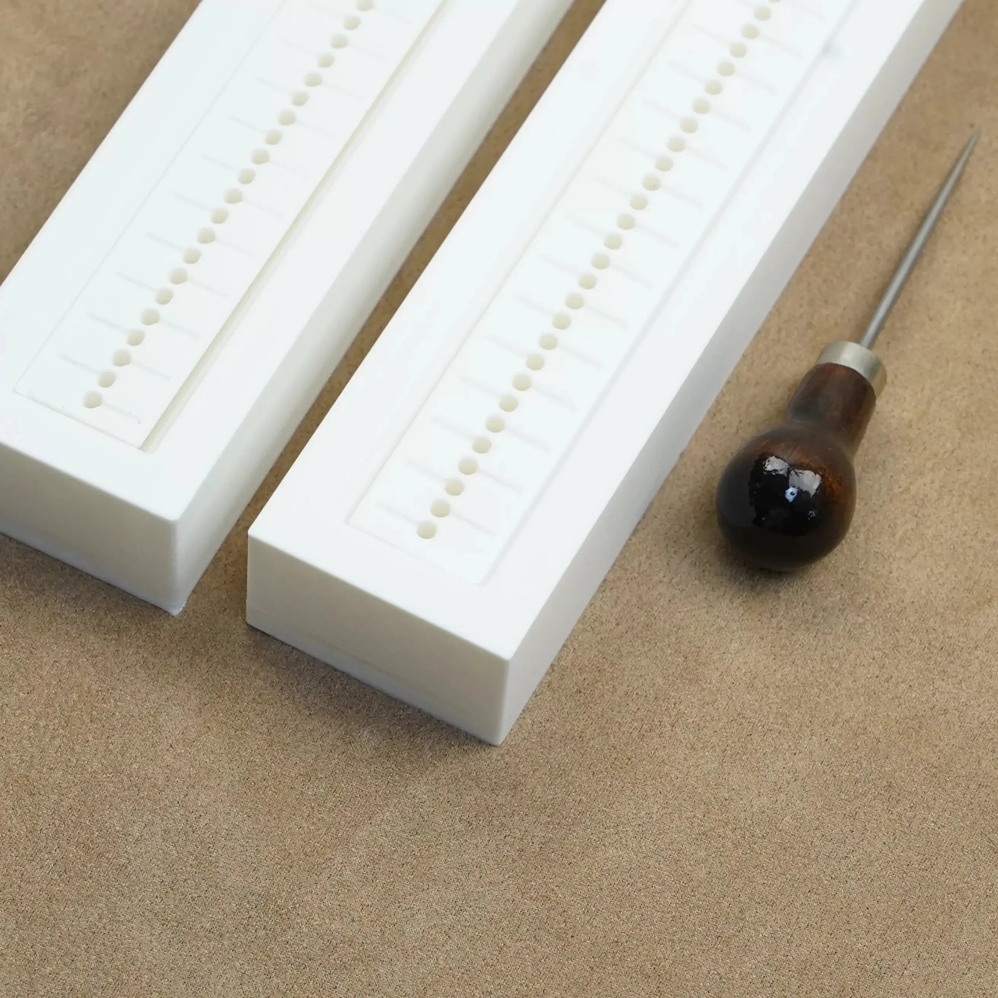 Hole punch guide tools for custom bookbinding and journaling projects on a leather surface.