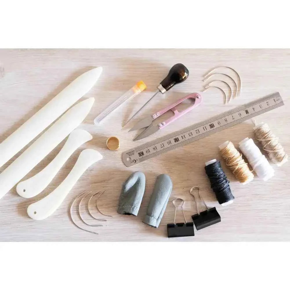 Complete bookbinding toolkit including tools and materials for crafting books and binding projects