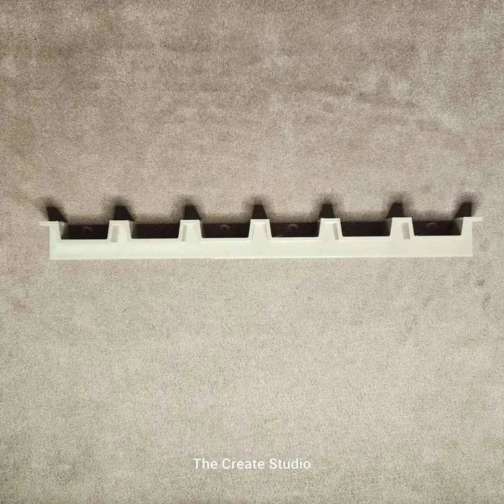 White plastic bee hive frame spacer by The Create Studio showing six frame slots on grey background