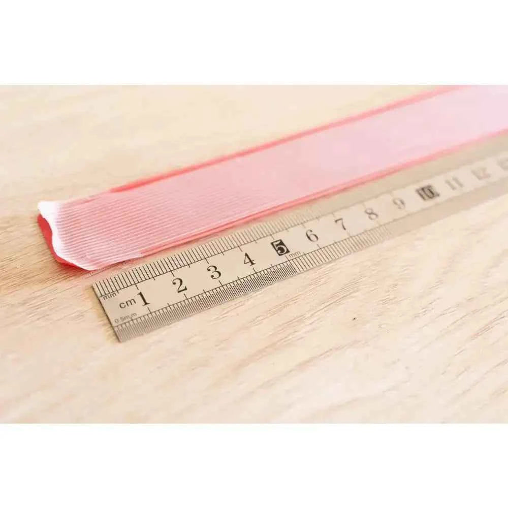 Pink book binding sewing set ribbon next to a measuring ruler for DIY projects