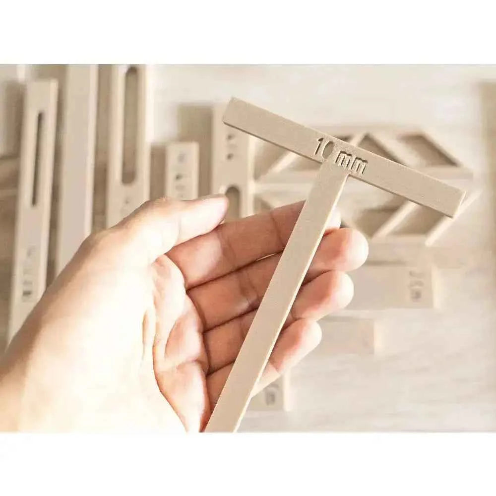 Hand holding a 10mm guide from a comprehensive bookbinding tools set for precise measurements