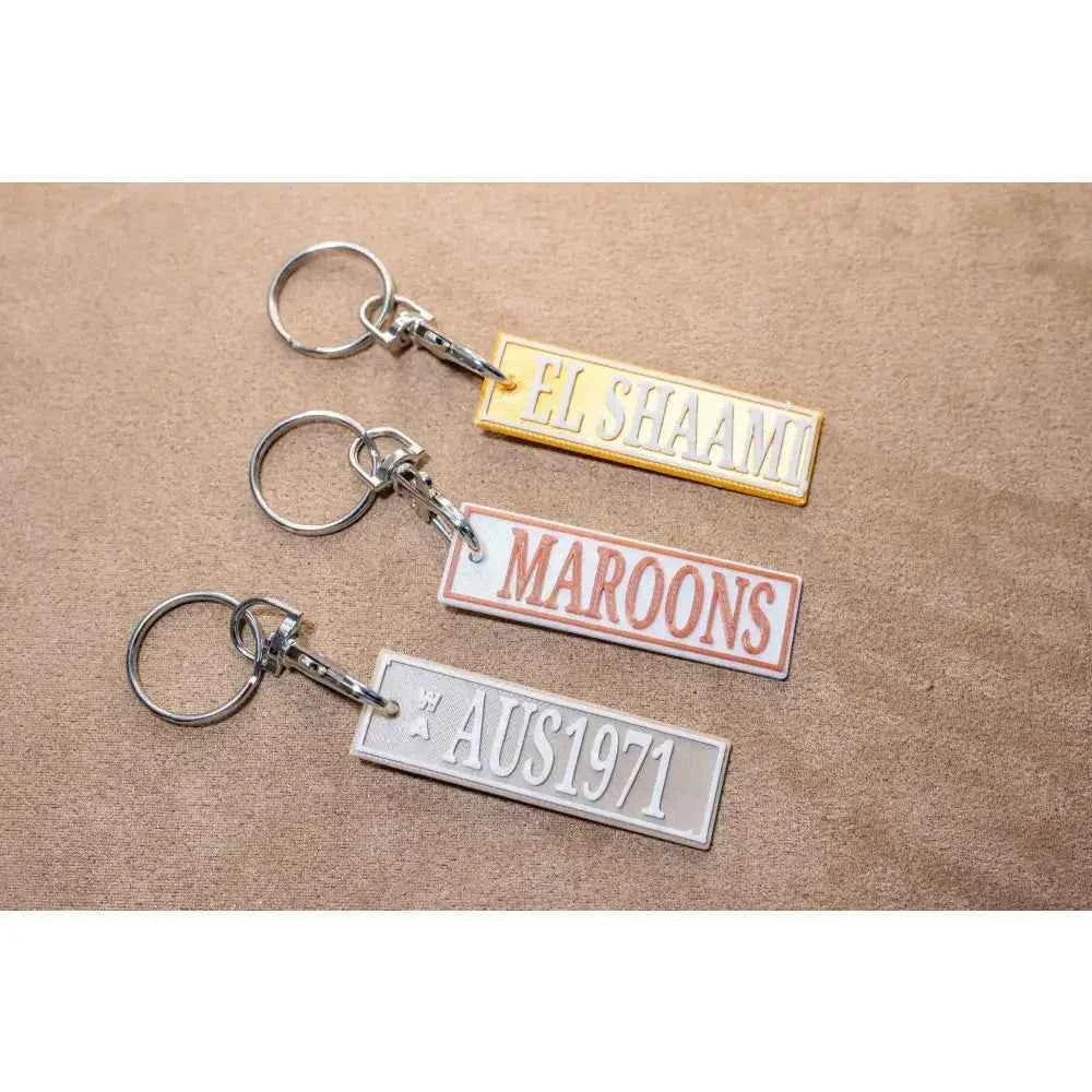 Set of Car Rego Keychains with unique designs featuring El Shaani, Maroons, and AUS1971