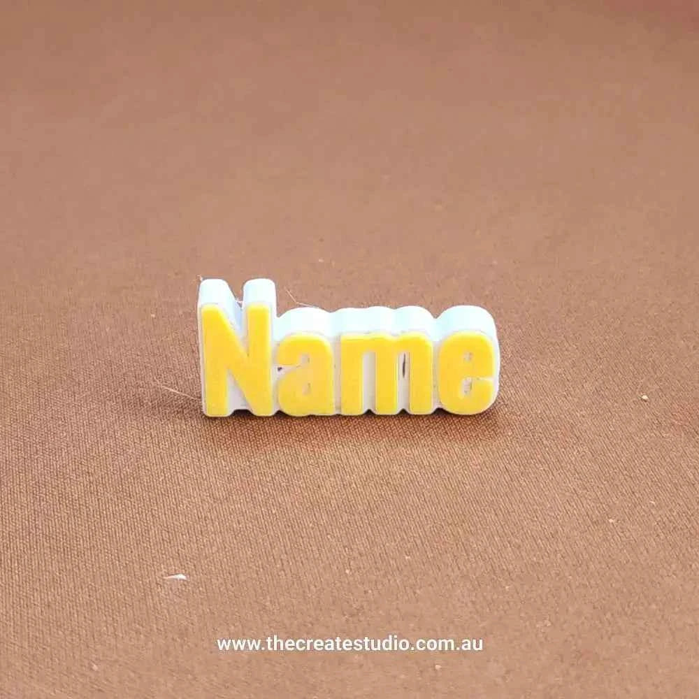 Personalized name charm for Crocs in yellow and white, ideal for custom footwear decoration
