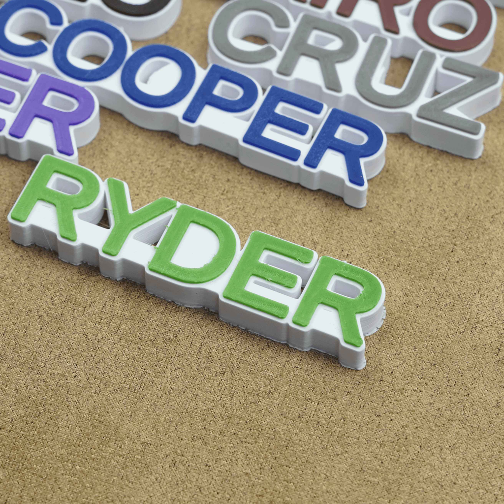 Colorful personalized name charms for crocs displayed on a textured surface