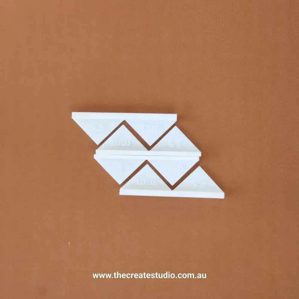 White triangular book binding corner pieces displayed on brown background from The Create Studio