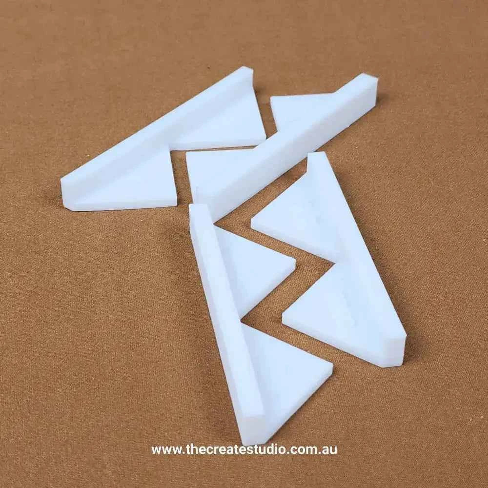 White plastic book binding corner pieces set laid on brown background for protecting book corners