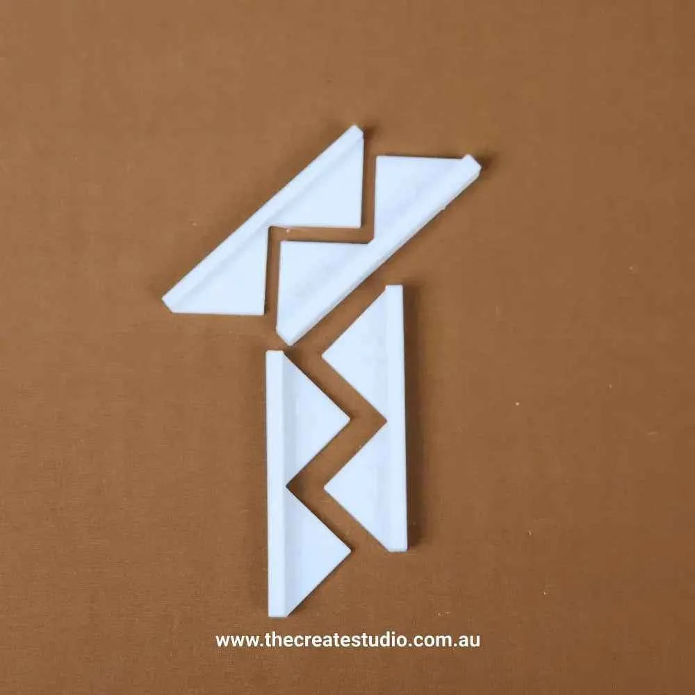 White plastic book binding corner pieces set displayed on brown background by The Create Studio