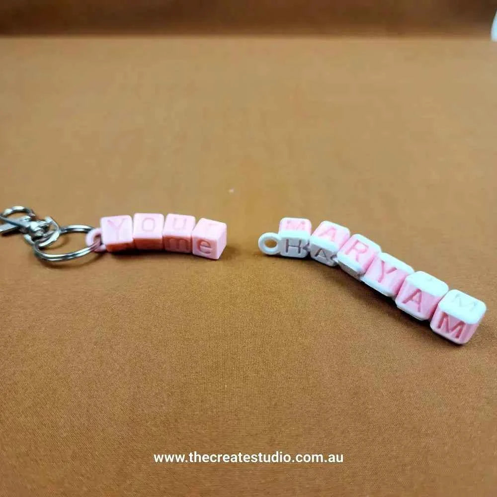 Personalised name keychain featuring pink and white bead letters spelling You and Maryam