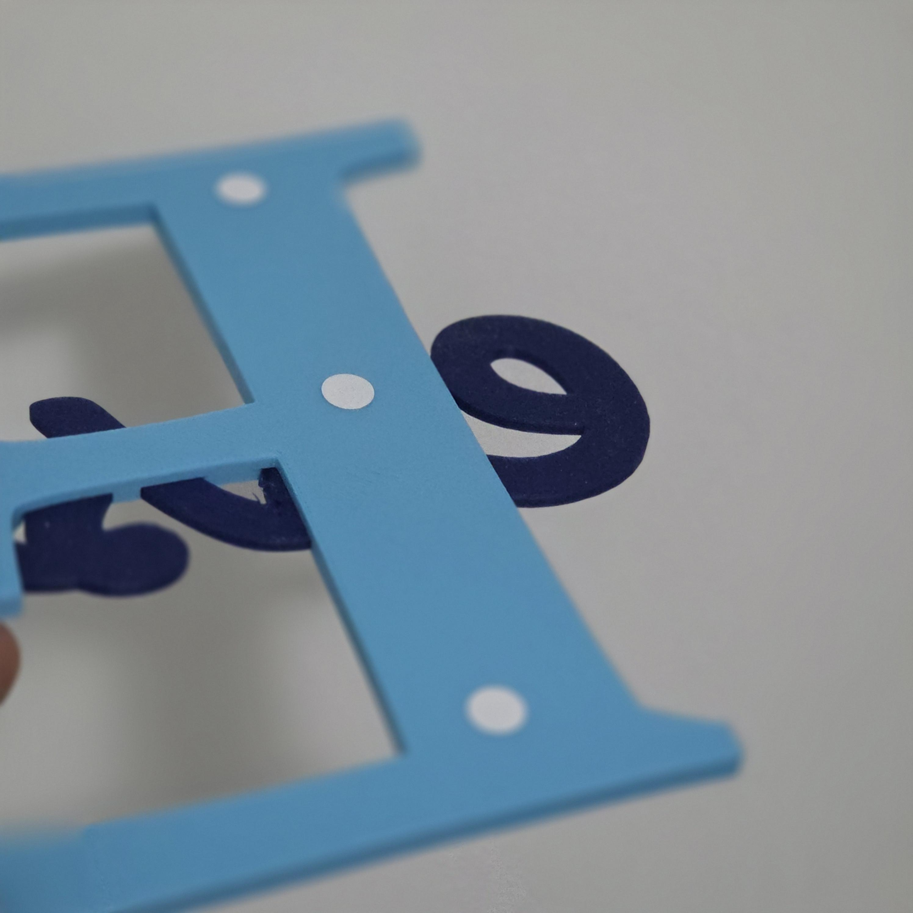 Custom baby room decor sign featuring a blue letter with contrasting elements for nursery decoration