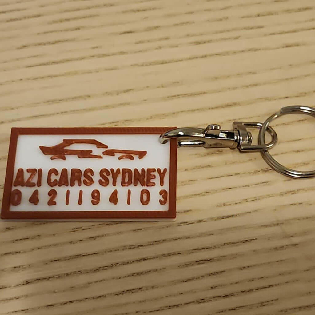 Custom keychains for companies featuring AZI Cars Sydney branding and contact details