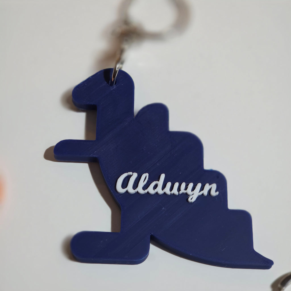 Custom name dino keychain in navy blue with the name Aldwyn in white lettering