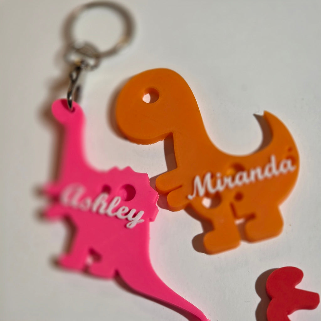 Personalised custom name dino keychain featuring pink and orange dinosaur designs with names