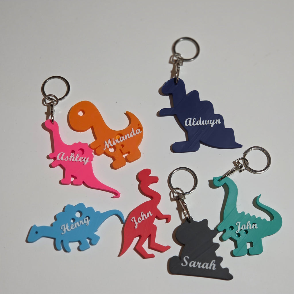 Colourful custom name dino keychain set featuring various dinosaur designs with personalised names