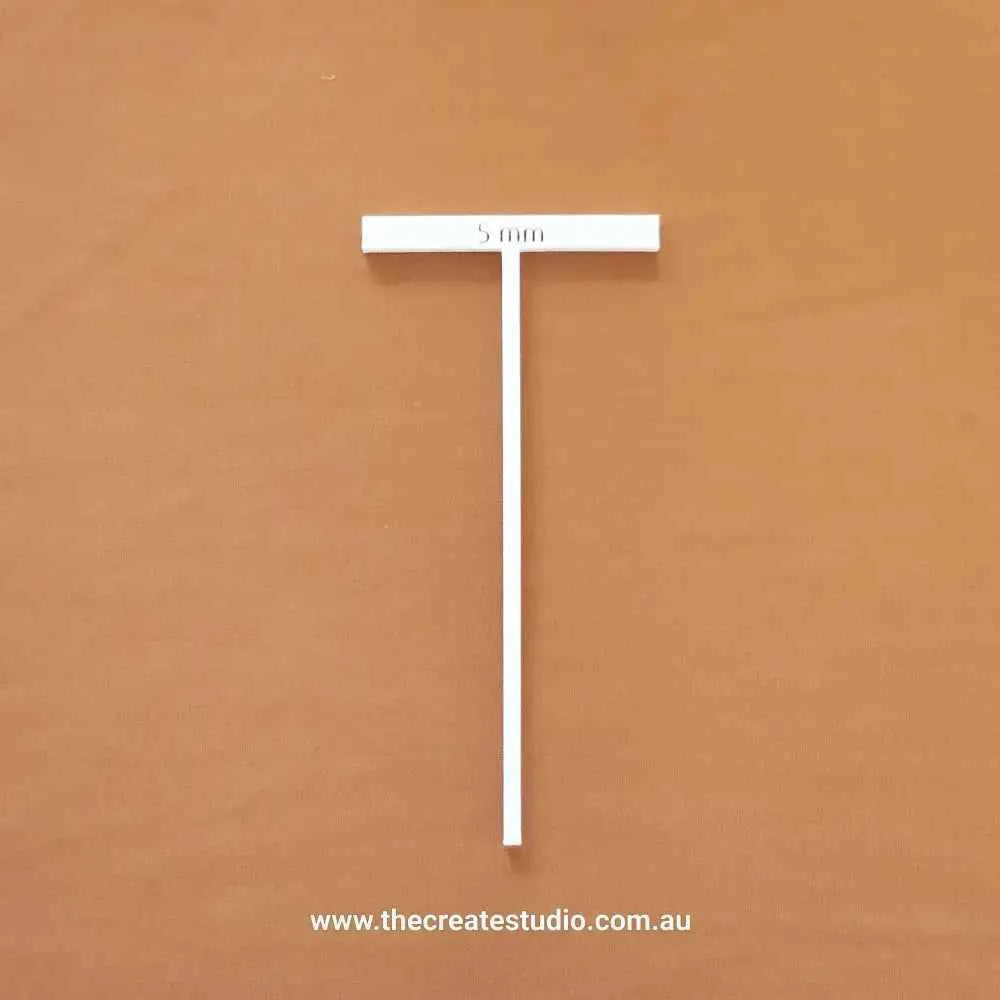 Essential bookbinding tools including a white T-square ruler for precise measurements in book binding