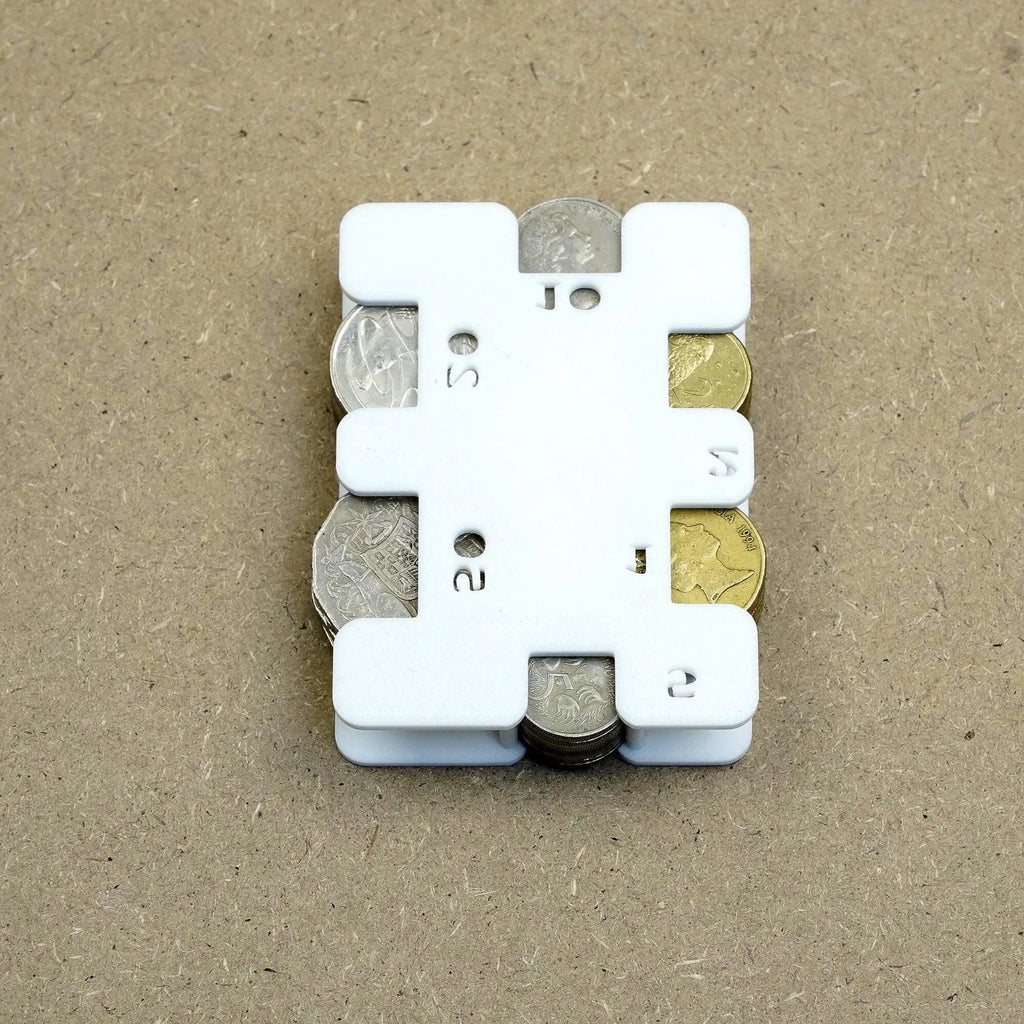 White plastic personal coin holder holding assorted UK coins on brown background personalised gift from The Create Studio