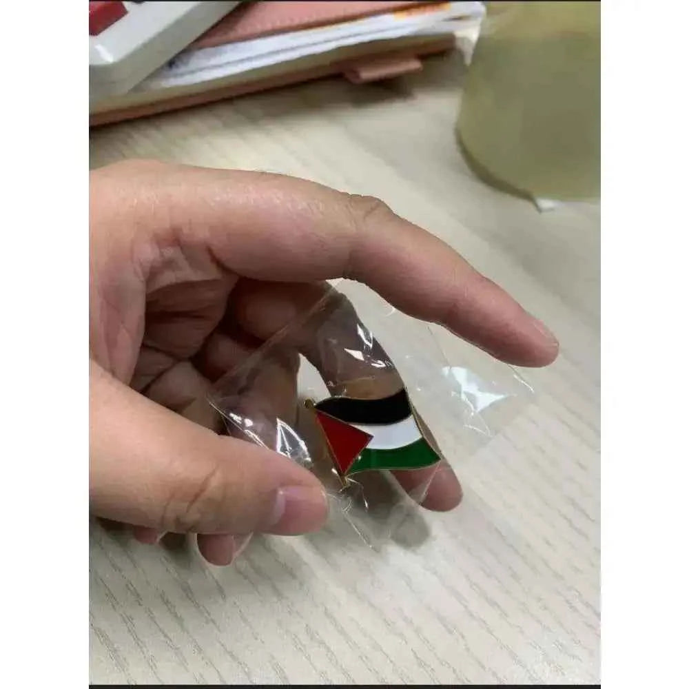 Palestine flag lapel pin in a protective sleeve, showcasing its vibrant colors in a hand