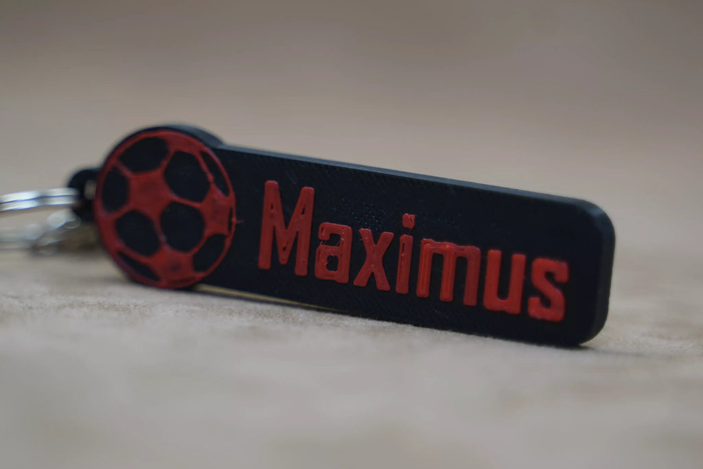 Personalised football keychain in black and red with the name Maximus and a football design