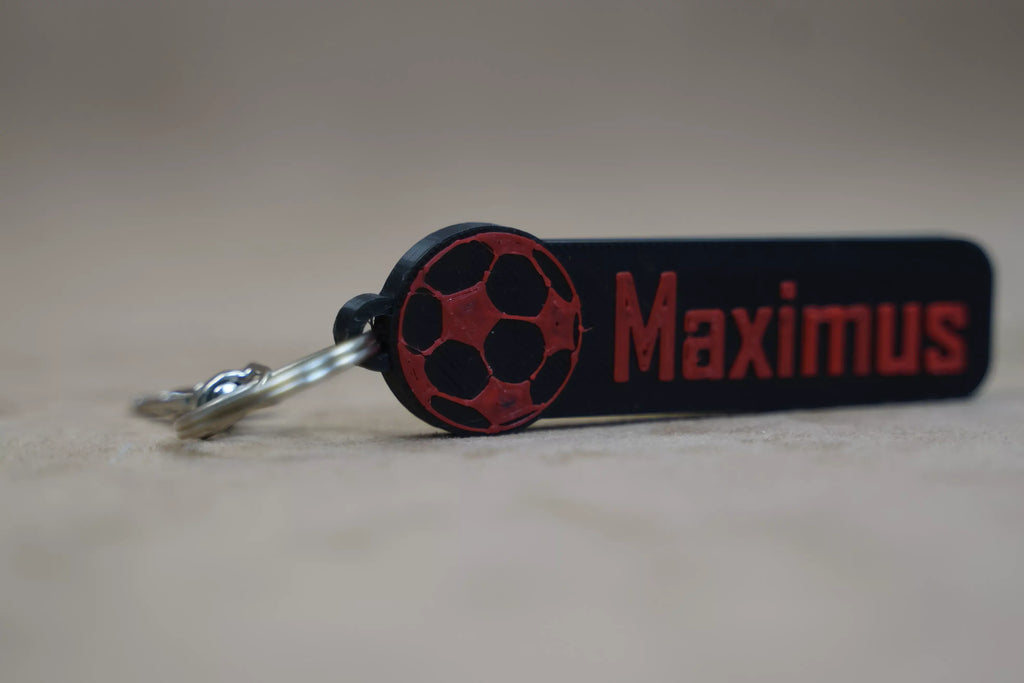 Personalised football keychain featuring the name Maximus in red and black design