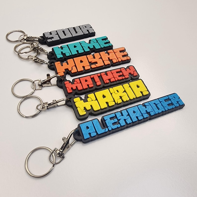 Colorful personalised name keychains featuring names like Alex, Maria, and Wayne in bold letters