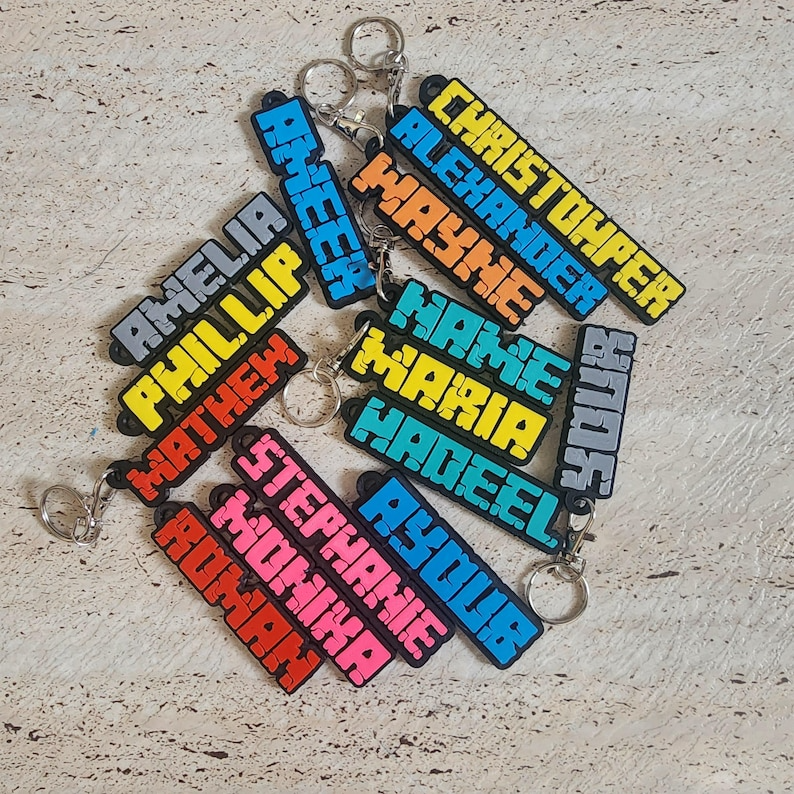 Colourful personalised name keychains from The Create Studio featuring various names in vibrant styles