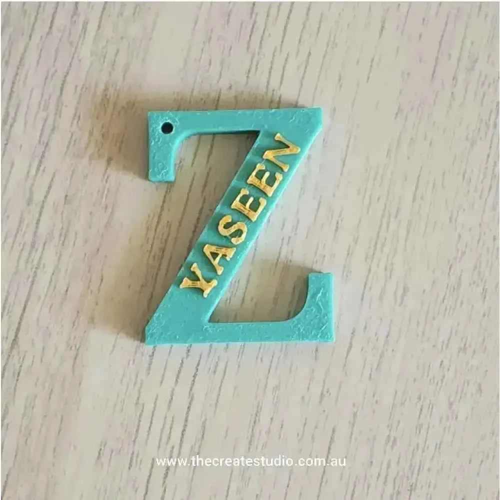 Personalized initial keychain with the letter Z in turquoise featuring gold lettering YASEEN