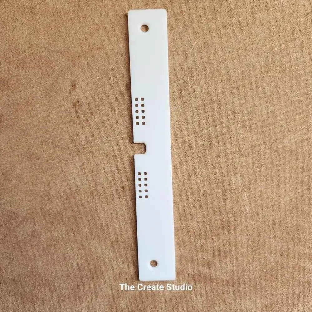 White plastic bee hive entrance reducer with ventilation holes and central notch on brown background